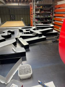 Fabrication of 3D sign letters for Total Auto Sales with rivets and tools visible in Southern Ontario workshop