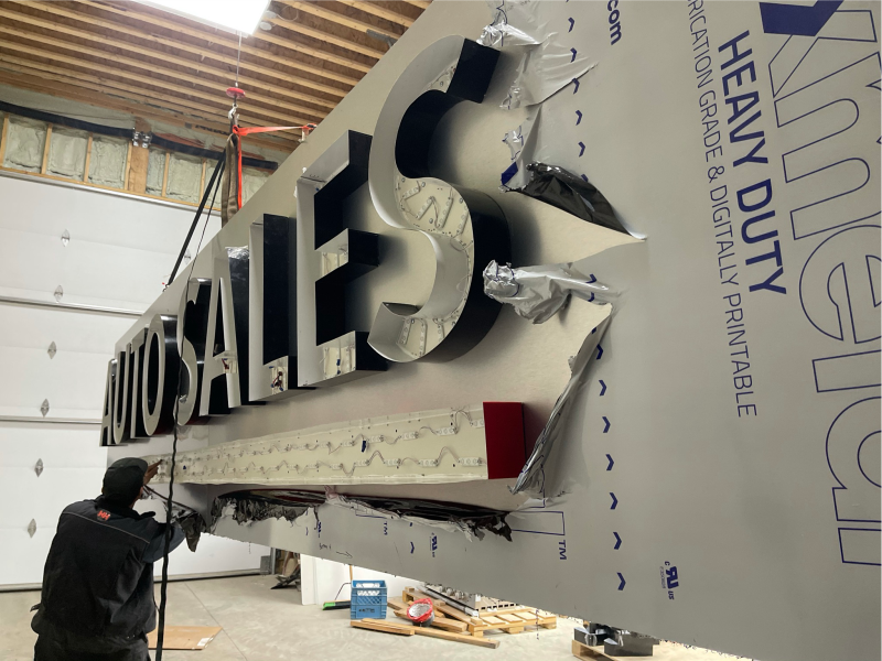 Innovative Sign Solution technician fabricating large illuminated channel letters for total Auto Sales sign in workshop