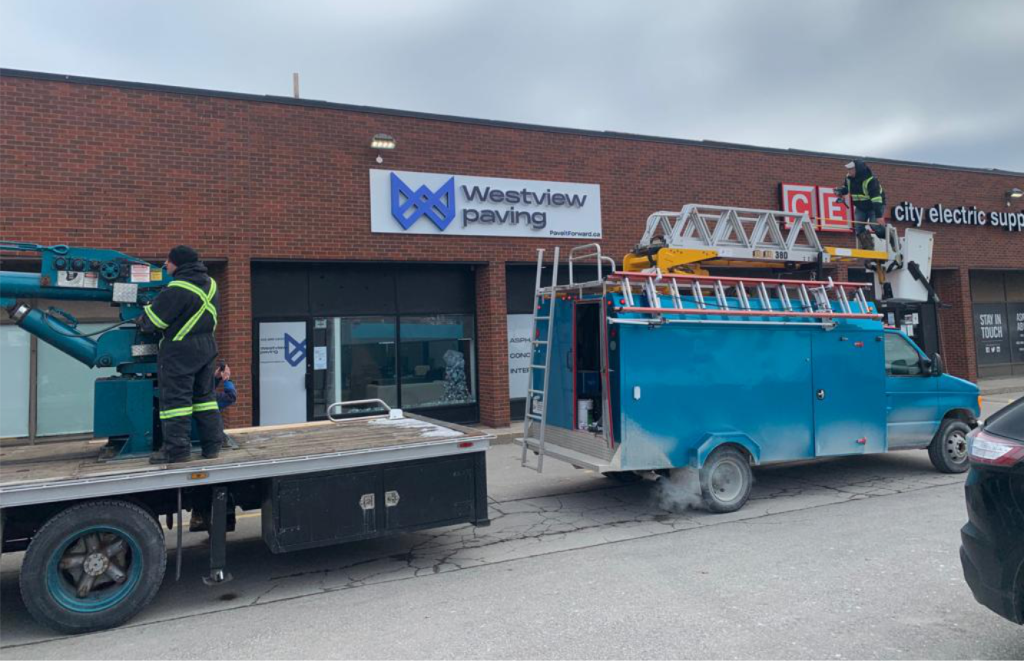 Innovative Sign Solution crew installing exterior business signs for Westview Paving and City Electric Supply using service trucks and lift equipment